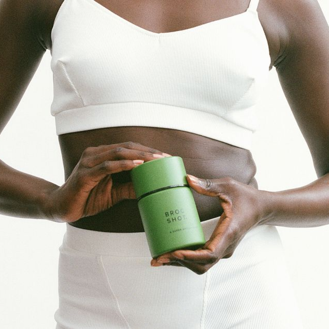 Front view of Broc Shot supplement jar showcasing the green cylindrical packaging and logo with a white torso background